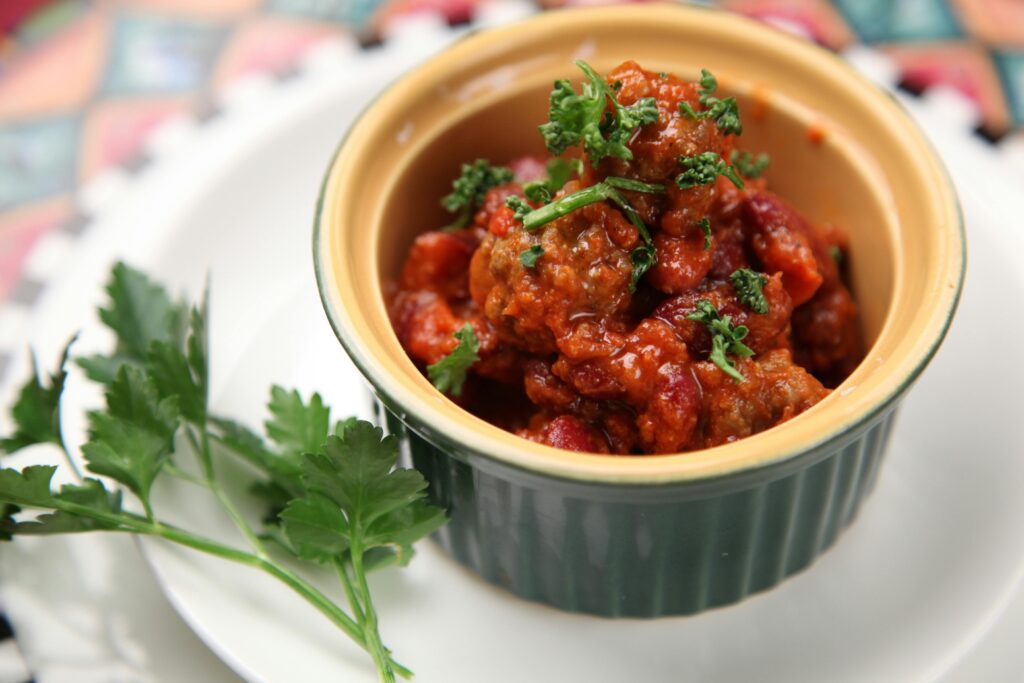 Close-up of a flavorful homemade chili dish garnished with fresh parsley, perfect for a cozy meal.