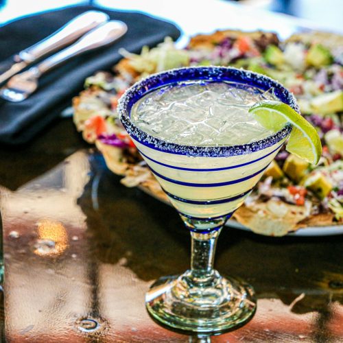 Close-up of a margarita with lime garnish on a restaurant table, perfect for a festive occasion.